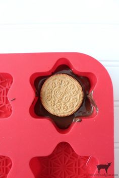 an oreo cookie in a chocolate molder on top of a red tray with white background