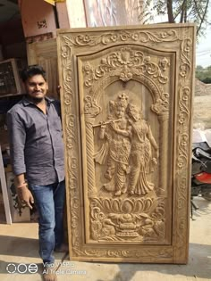 a man standing next to a carved wooden door