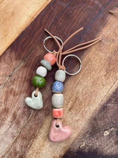 several different colored beads are hanging from a string on a wooden table with other items in the background