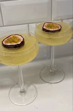 two wine glasses filled with drinks sitting on top of a counter next to each other