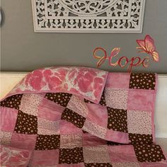 a pink and brown quilt with the word hope on it next to a white doily