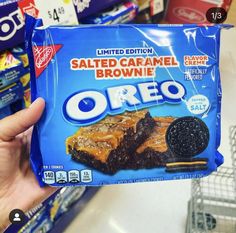 someone holding up a bag of oreo salted caramel brownie in a store