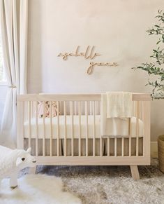 a white crib in a nursery with a baby's name on the wall