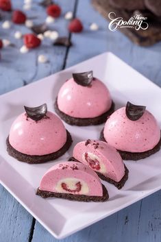 four desserts on a white plate with chocolate and raspberry frosting in the middle