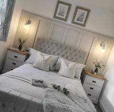 a bed with white linens and pillows in a small room next to two framed pictures on the wall