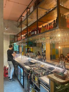 a man standing in front of a bar filled with lots of bottles and wine glasses