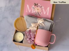 a box filled with pink and white items next to a candle, napkins, and teacup