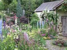 a garden with lots of flowers and a statue