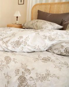 an unmade bed with white sheets and brown pillow cases in a small room next to a lamp