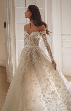 a woman in a white wedding dress is standing on the floor with her hands behind her back