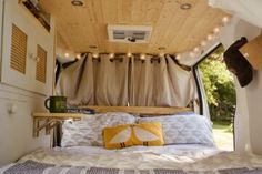 a bed in the back of a camper with lights hanging from it's ceiling