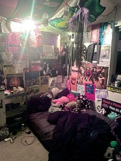 a bed room with a bunch of stuff on the wall and posters all over the walls