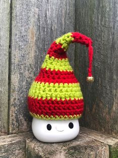 a crocheted gnome hat sitting on top of a wooden fence next to an apple