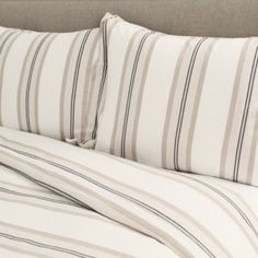 a bed with striped sheets and pillows on it