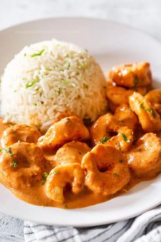 a white plate topped with rice and meat covered in gravy on top of a table