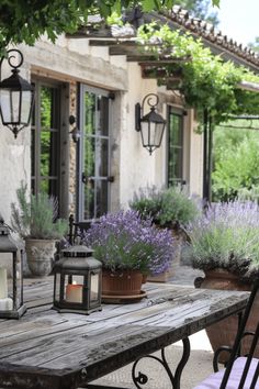 a wooden table topped with lots of potted plants next to a patio covered in purple flowers