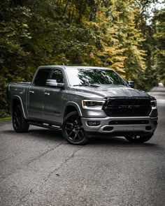 a gray ram truck parked on the side of a road in front of some trees