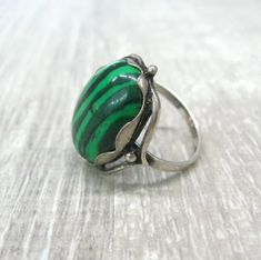 Vintage fashion jewelry, Malachite imitation woman's ring in size 9. Only 1 item available, not adjustable and not resizeable. Very good condition. Size: 9 ( US and Canada ), R 3/4 ( UK and Australia ), 19 ( Europe ). Stone: stripy green MAlachite imitation ( AKA pressed stone or reconstituted malachite ) The stone is oval shape, measuring 14X10 mm and standing 7 mm tall over the finger surface. Material: Silver plated brass. This is a high quality ring in electric silver plate with 980 silver t Green Open Ring Jewelry For May Birthstone, Handmade Adjustable Green Emerald Ring, Vintage Green Turquoise Cabochon Ring, Adjustable Green Emerald Ring, Adjustable Fit Emerald Ring, Unique Green Cabochon Ring, Unique Green Gemstone Rings, Adjustable Green Emerald Ring For Anniversary, Adjustable Green Rings For May Birthstone