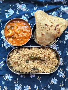 three metal bowls filled with food on top of a blue cloth covered table next to each other