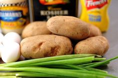 potatoes, onions and garlic on a cutting board with seasoning bottles in the background