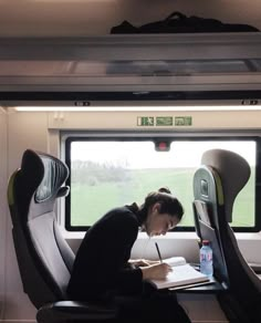 a woman sitting at a desk in front of a laptop computer on top of a train