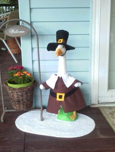 a statue of a duck dressed as a pilgrim with a broom and hat on the front porch