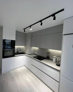 an empty kitchen with white cabinets and black counter tops on the wall, along with lights hanging from the ceiling