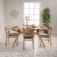 a dining room table with chairs and plates on top of it in front of a potted plant