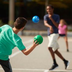 two young boys playing frisbee with each other on a court while another boy watches