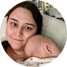 a woman holding a baby in her arms and looking at the camera with a smile on her face