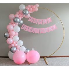 a pink and silver balloon arch with happy birthday banner on it next to some balloons