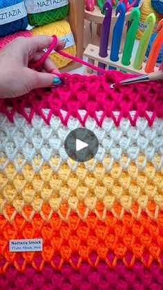 a person is crocheting on a colorful blanket with scissors and yarn in the background