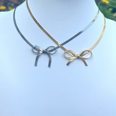 Introducing the must-have accessory of the season: our Bow Choker Necklace. Adorned with the prettiest bow, this elegant piece adds a touch of luxury to any outfit. Make a statement with this exclusive necklace, the perfect blend of fashion and art. Elevate your style with our Bow Choker Necklace today. Made to last! Non-Tarnish and Water Resistant, Hypoallergenic Heart Pendant 12.5 inches long +3.5 inches ext Lobster Closure 18K Gold Plated over 316L Stainless Steel base Adjustable Ribbon Necklaces For Party, Elegant Bow Choker Jewelry, Elegant Bow Choker Necklace, Feminine Evening Jewelry With Bow, Elegant Gold Necklace With Bow Detail, Elegant Bow Necklace For Party, Elegant Gold Necklace With Bow, Elegant Party Necklace With Bow, Chic Jewelry With Butterfly Knot For Parties