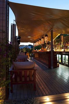 an outdoor bar is lit up at night with lots of lights on the deck and in the background