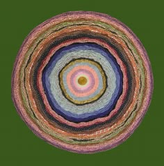 a circular rug with multicolored yarn in the center on a green background photo