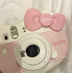 a pink and white camera sitting on top of a bed next to a stuffed animal