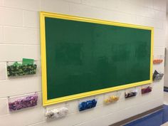 a green board mounted to the side of a wall in a school hallway with candy on it