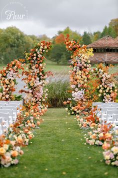 an outdoor ceremony setup with white chairs and floral archways on the grass, surrounded by flowers