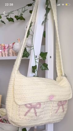 a crocheted purse hanging from a ladder in front of a shelf with stuffed animals