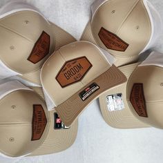 four hats with brown leather patching on the front and back, sitting on a white surface