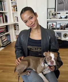 a woman holding a small dog in her lap while sitting on top of a wooden floor