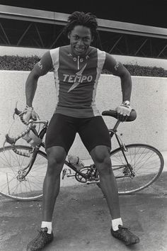 a black and white photo of a man standing next to two bikes