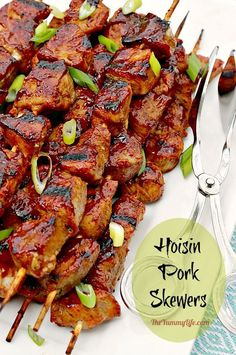 the skewers are covered in barbecue sauce and green onions, along with forks