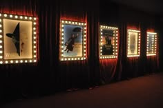 a row of lighted mirrors on the side of a wall in front of red curtains