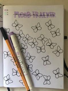 an open notebook with butterflies drawn on it and two pencils laying next to it