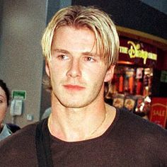 a man with blonde hair is standing in front of a woman and looking at the camera