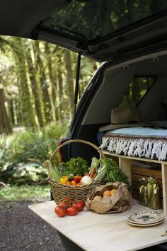 the back end of a van filled with fresh vegetables and fruits on a picnic table