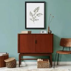 a living room with a chair and a painting on the wall next to a wooden cabinet