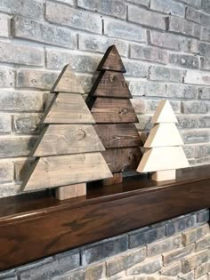 three wooden christmas trees sitting on top of a mantle