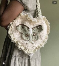 a woman holding a crocheted heart shaped purse with an owl on the front